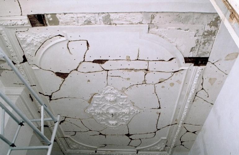 Gescheurd gipsplafond, de plafonds waren ernstig beschadigd, grote stukken brokkelden af. In een kamer is het hele plafond zelfs volledig verloren gegaan.