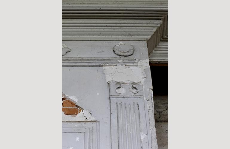 Pilasterkapiteel op schouw, een ernstig beschadigd kapiteeltje en andere kapotgeslagen ornamenten op de schouw.